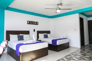 two beds in a room with blue and white walls at Pa&acute;Xa Mama Hotel Boutique in Canc&uacute;n