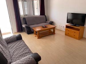ein Wohnzimmer mit einem Sofa, einem TV und einem Tisch in der Unterkunft Rach Agaete in Agaete