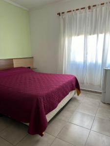1 dormitorio con cama morada y ventana en HOTEL DIAMANTE en Resistencia