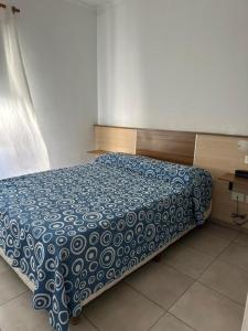 a bed with a blue and white comforter in a bedroom at HOTEL DIAMANTE in Resistencia