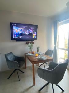 a dining room with a table and chairs and a tv at Apartament Bella in Międzyzdroje