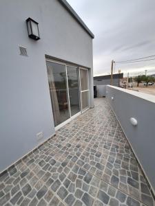 een patio van een wit gebouw met een stenen vloer bij CALA DEPARTAMENTO in Alta Gracia