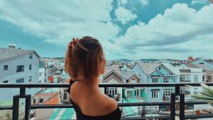 Una mujer parada en un balcón con vistas a una ciudad en PoWill Home, en Da Lat