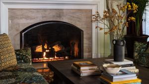 a living room with a fireplace and a table with books at La Playa Hotel in Carmel