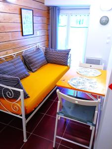 Un pequeño dormitorio con una cama amarilla y una mesa. en Gîte Les Hirondelles - Bord de mer et campagne, en Tracy-sur-Mer