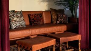 a brown leather couch with pillows and two stools at La Playa Hotel in Carmel +19 photos