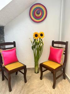 Dos sillas y un jarrón de flores en una habitación en Casa Balthazar Hostel, en Quito