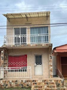 een bakstenen huis met een balkon en rode deuren bij Guesthouse Celeste in São Tomé