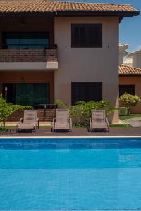 two lounge chairs and a swimming pool in front of a house at A 450m da PRAIA de TAPERAPUAN, no 2 pavimento, Piscina, Churrasqueira, 2 quartos, até 6 pessoas, WiFi independente 300 mbs, Estacionamento Gratuito, Próximo a mercado e restaurantes in Porto Seguro