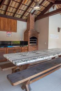 uma grande mesa de madeira numa cozinha com um forno de tijolos em A 450m da PRAIA de TAPERAPUAN, no 2 pavimento, Piscina, Churrasqueira, 2 quartos, até 6 pessoas, WiFi independente 300 mbs, Estacionamento Gratuito, Próximo a mercado e restaurantes em Porto Seguro