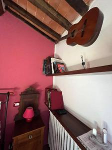 une chambre avec une guitare sur un mur rose dans l'établissement La Rocca Sovrana - Casa Vacanze, à Aramo