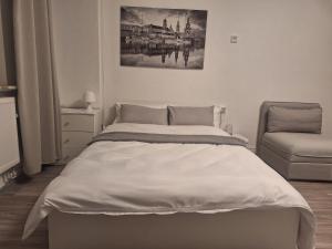 Studio Apartment 10 - 1R1 في إيسن: غرفة نوم بيضاء بسرير وكرسي