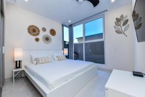 a white bedroom with a large white bed and a large window at Aracari 1 in Palm-Eagle Beach