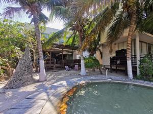 uma piscina em frente a uma casa com palmeiras em Acogedora villa con alberca em Xtampú