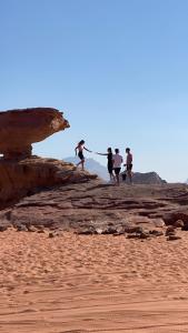 a group of people walking on rocks on the beach at Yellow Star Camp Wadi Rum in Wadi Rum
