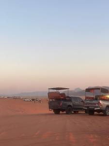 a truck parked in the desert with a bus on the back at Yellow Star Camp Wadi Rum in Wadi Rum