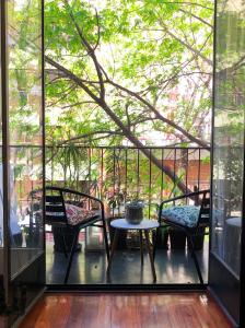 Un balcón con 2 sillas, una mesa y un árbol en Te invito a Compartir mi Depto. Artlovers. Solo Damas. en Buenos Aires