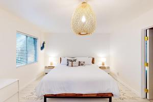 a white bedroom with a bed and a chandelier at Modern Pines Hideaway in Crestline