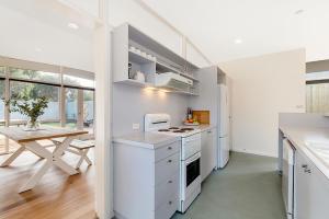 a kitchen with white appliances and a table in it at The 20th Hole in Point Lonsdale