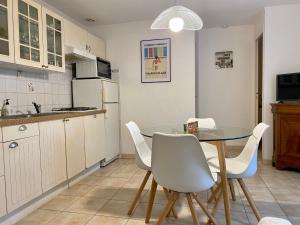 eine Küche mit einem Glastisch und weißen Stühlen in der Unterkunft Gîte Saint-Michel-Chef-Chef, 3 pièces, 4 personnes - FR-1-306-819 in Saint-Michel-Chef-Chef