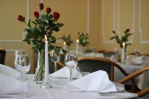 una mesa con copas de vino y un jarrón con rosas rojas en Hotel Flora, en Fredersdorf