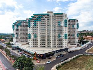 un grand bâtiment avec des voitures garées dans un parking dans l'établissement Apartamento Enjoy Olimpia Park Resort, ao lado do Thermas, à Olímpia