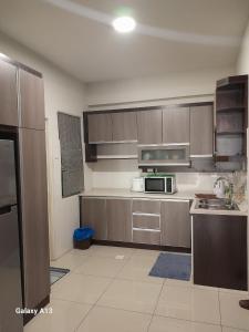 eine Küche mit Holzschränken und einer Mikrowelle in der Unterkunft K. Riverfront apartment in Ipoh