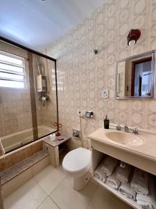 y baño con aseo, lavabo y ducha. en Ipanema 2 quartos à 3 quadras da praia com garagem, en Río de Janeiro