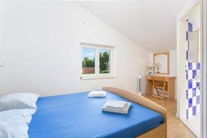 Un dormitorio con una cama azul y un escritorio. en Apartment Seget Vranjica 14409a, en Donji Seget 25 fotos más