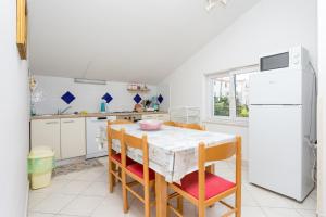 Una cocina con mesa y sillas y un refrigerador. en Apartment Seget Vranjica 14409a, en Donji Seget