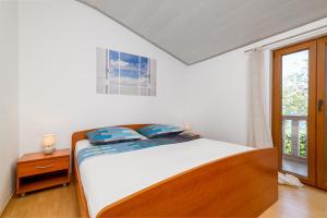 a bedroom with a bed and a window at Apartments by the sea Duga Luka - Prtlog, Labin - 2335 in Labin