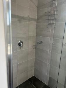 cabina de ducha con puerta de cristal y ducha en Beechworth Lake Sambell Caravan Park, en Beechworth
