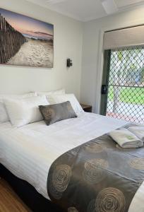 Un dormitorio con una gran cama blanca y una ventana en Beechworth Lake Sambell Caravan Park, en Beechworth