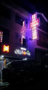 un bâtiment avec des panneaux de néon sur son côté dans l'établissement Hotel D'Gloria, à Churín