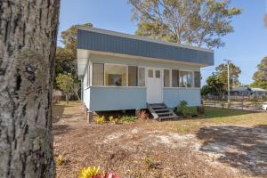 ein kleines weißes Haus mit einem Baum in der Unterkunft Entire Beach House on Bribie Island in Bongaree