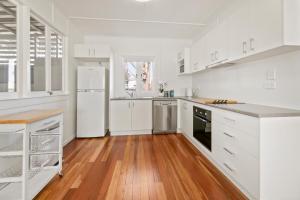a white kitchen with white appliances and wooden floors at Entire Beach House on Bribie Island in Bongaree