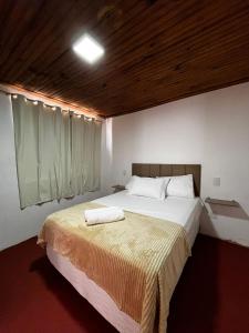 a bedroom with a large bed with a wooden ceiling at Casa do Chafariz Tiradentes in Tiradentes