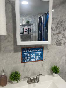 un bagno con specchio sopra un lavandino di A cool unique place from home a Elmont