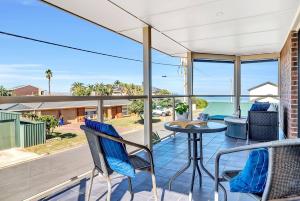einen Balkon mit einem Tisch und Stühlen sowie Meerblick in der Unterkunft Laidback Seaford Family Retreat 200m from Beach in Seaford