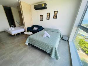 a bedroom with a bed and a couch and a window at Salguero Suites - Playa Salguero - By INMOBILIARIA VS in Santa Marta