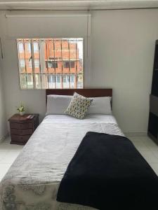 1 dormitorio con 1 cama grande y ventana en APARTAESTUDIOS BOGOTÁ, en Bogotá