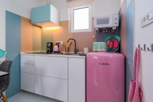 uma cozinha com um frigorífico cor-de-rosa e um lavatório em Apartments and rooms by the sea Banjol, Rab - 5077 em Rab