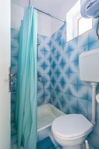 uma casa de banho em azulejos azuis com um WC e uma banheira em Apartments and rooms by the sea Banjol, Rab - 5077 em Rab