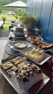 a long table filled with different types of desserts at Glamping casal - mini chale mobiliado com colchão casal roupa de cama travesseiros - Rancho Perene estação rural in Jaraguá do Sul