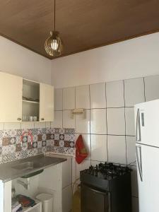 a kitchen with a stove and a white tiled wall at Casa Vermelha in Morro de São Paulo