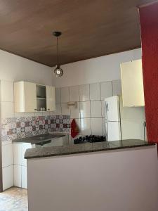 a kitchen with white cabinets and a white refrigerator at Casa Vermelha in Morro de São Paulo