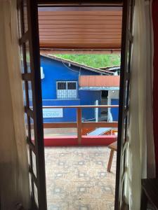 an open door to a balcony with a blue building at Casa Vermelha in Morro de São Paulo