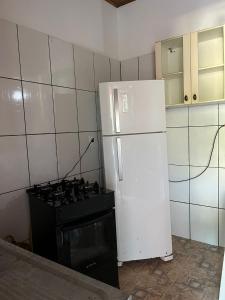 a kitchen with a white refrigerator and a stove at Casa Vermelha in Morro de São Paulo