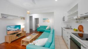 a living room with a blue couch and a kitchen at Yamba Daze Sunset in Yamba +9 photos