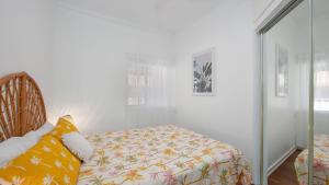 a bedroom with a bed with a yellow and white blanket at Yamba Daze Sunset in Yamba